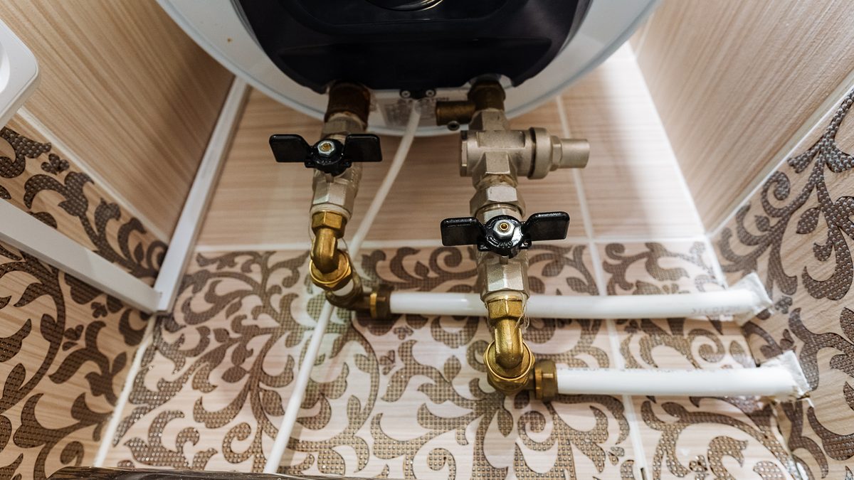 Isolating valves and supply pipes beneath a wall-mounted water heater