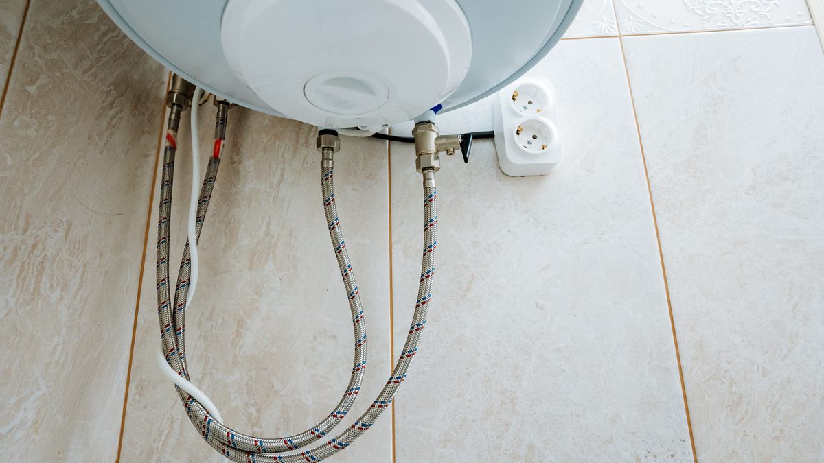 Braided supply hoses and a shutoff valve under a wall-mounted water heater